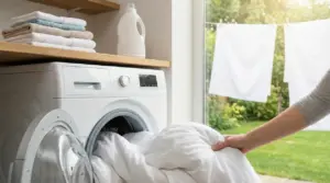 Una persona inserisce lenzuola bianche in una lavatrice davanti a una finestra soleggiata