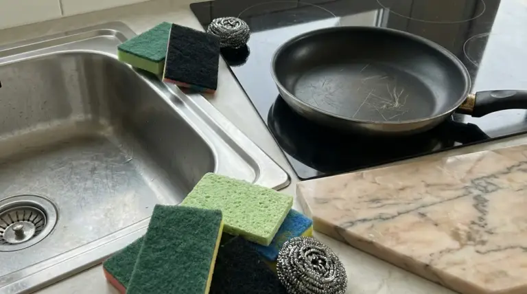 Spugne abrasive e pagliette metalliche vicino a lavello e padella graffiata